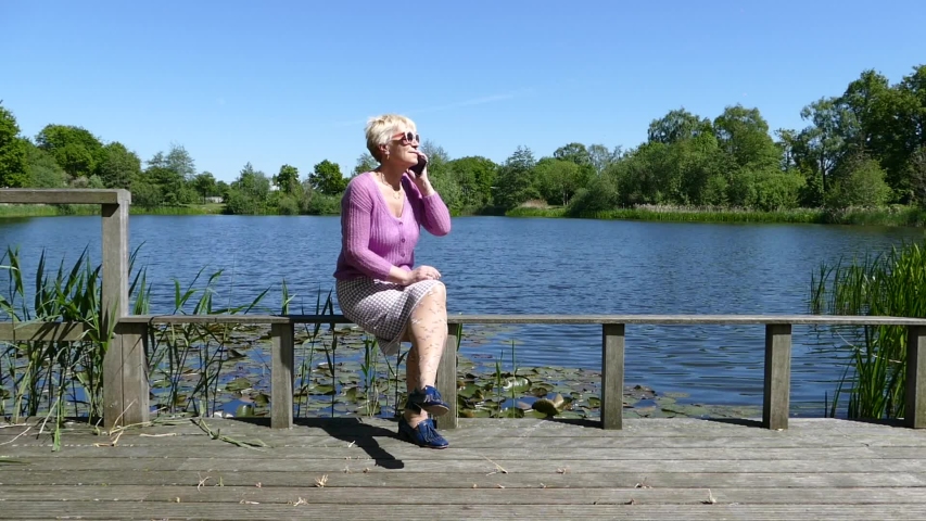 European woman of middle age just mobile in a park to the pond.