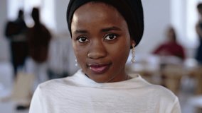 Close-up portrait of young happy African business woman in ethnic headwrap posing, smiling at modern trendy office. - Powered by Shutterstock - Get 15% off with code: PIKWIZARD15