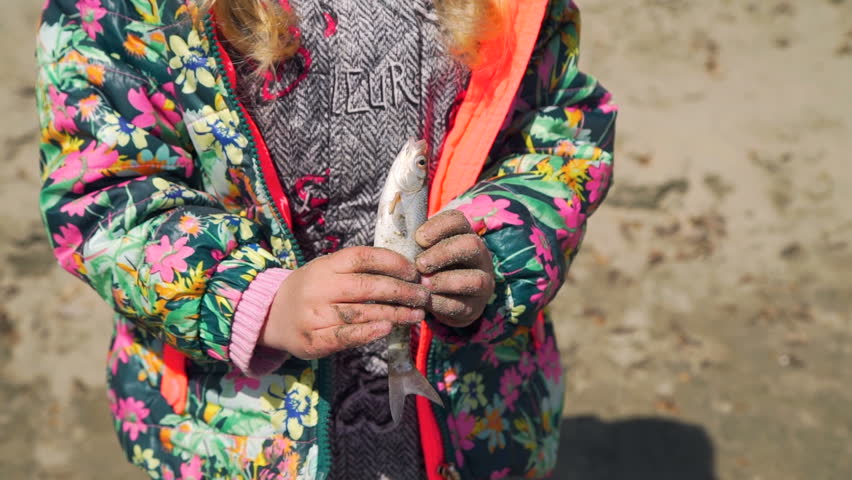 Young Girl Holding Freshly Caught Fish in her Hands in Sunny Spring Day. The Concept of Fishing and Leisure Activity in Nature