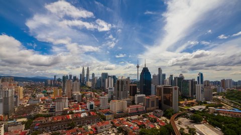 Aerial time lapse view of Kuala Lumpur city skyline with busy streets in Malaysia on a blue skies. Zoom out motion timelapse.