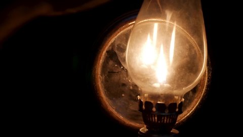 Close-up of lighting an old antique oil lamp in the dark