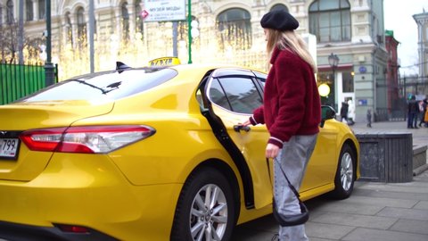 Woman getting in yellow cab in city center