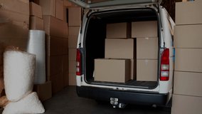 Rear view of a Caucasian deliveryman loading packages in the back of a van. Digital animation of binary codes are flying around in the foreground - Powered by Shutterstock - Get 15% off with code: PIKWIZARD15