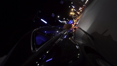 Fast black car driving at night road through the city, view from wheel, timelapse. Footage. Modern vehicle moving along the busy city in the evening, road trip concept.
