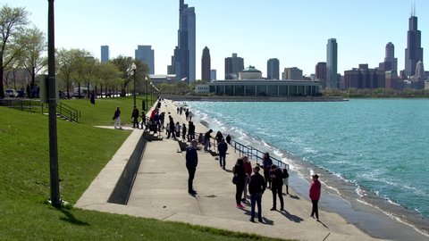 Chicago,IL/United States-May 13th 2019:  Tourist are having fun in Chicago near lake Michigan taking pictures and selfie on a nice afternoon. the clear blue sky shows the downtown Skyline of city 