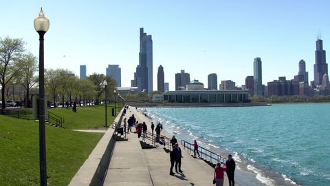 Chicago,IL/United States-May 13th 2019:  Tourist are having fun in Chicago near lake Michigan taking pictures and selfie on a nice afternoon. the clear blue sky shows the downtown Skyline of city 