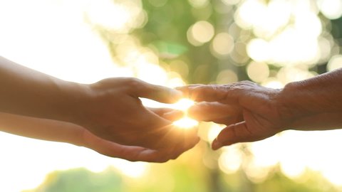 Hand of young man holds the hand of an elderly person with love and warm feeling, metaphor Help for the eldery, nursing home, Help to relatives, warm family