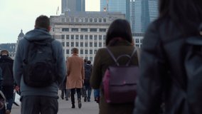 Crowd of pedestrian commuters crossing London Bridge on their way to work on cool morning in early May.  Slow motion version – real time version also available. Clip 27 of 66