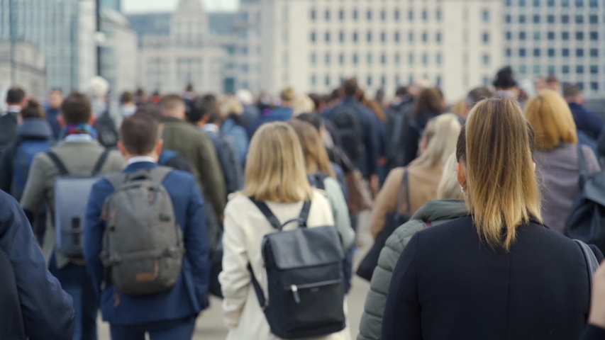 Crowd of pedestrian commuters crossing London Bridge on their way to work on cool morning in early May.  Slow motion version – real time version also available. Clip 33 of 66 Royalty-Free Stock Footage #1029484541