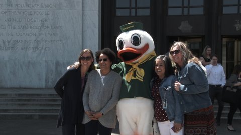 SALEM, OREGON / USA - MAY 2019: A group of sport fans gather at the state capitol building and get photo taken with Oregon Duck mascot.