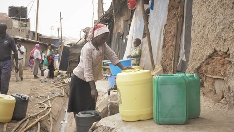 A young African lady filling water in the water cans at water filling centre in Kibera, Nairobi, Kenya (April 2019)