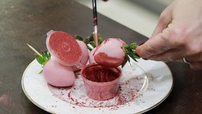 Ripe strawberry covered with pink chocolate is painted with pink shiny food paint. Zoom motion, close-up