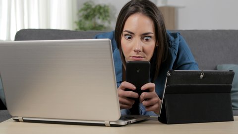 Obsessed woman using multiple devices sitting in the living room at home