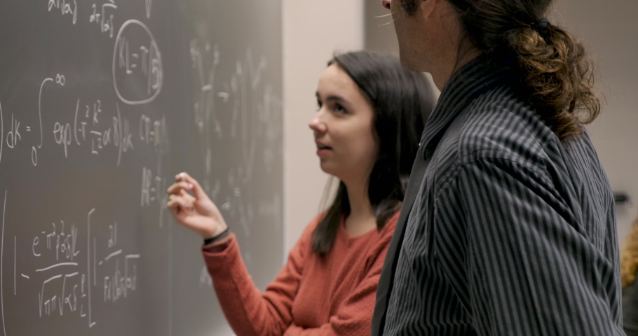 Male professor teaching a young female student in her early 20s or late teens a complicated math or science lesson in a college or high school classroom Royalty-Free Stock Footage #1029494735