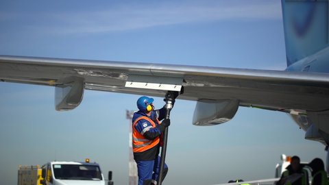 Airport airplane crew refueling aircraft on airline by technical staff maintenance ground. Preparing airplane for departure. service worker using fuel hose on aircraft wing, jet aviation fuel kerosene