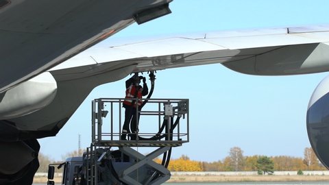 Airport airplane crew refueling aircraft on airline by technical staff maintenance ground. Preparing airplane for departure. repair of aircraft service worker use fuel hose on aircraft wing, on stairs