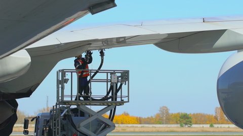 Airport airplane crew refueling aircraft on airline by technical staff maintenance ground. Preparing airplane for departure. repair of aircraft service worker use fuel hose on aircraft wing, on stairs