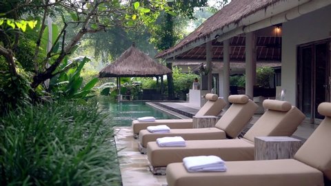 Row of lounging chairs on pool terraces in exotic hotel. Outside area with pool