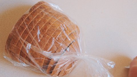 Male hands open plastic bag with bread on the table. The packaging is closed on a latch.