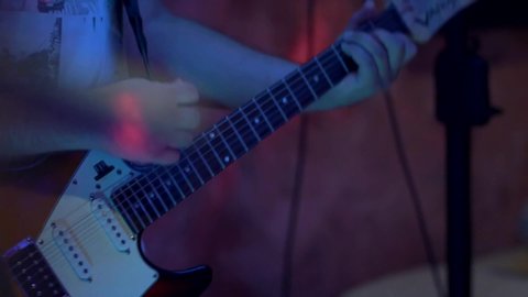 Slow motion shot of guitar player during concert. Closeup of musician strumming guitar.