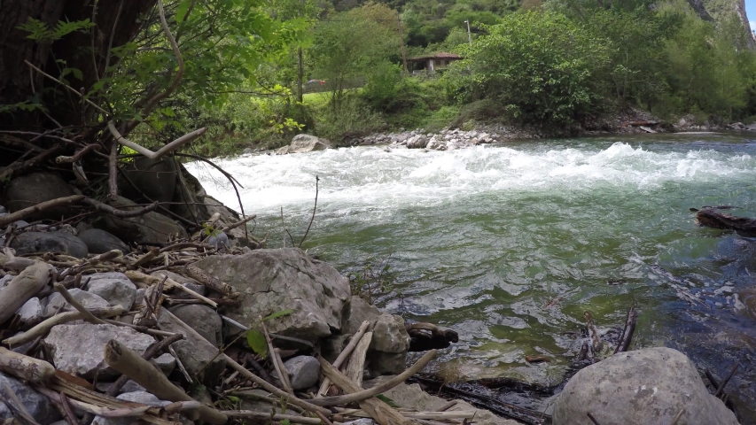 River running its green waters fron a rocky shore side