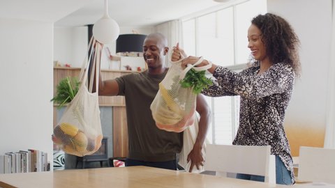 Couple Returning Home From Shopping Trip Unpacking Plastic Free Grocery Bags