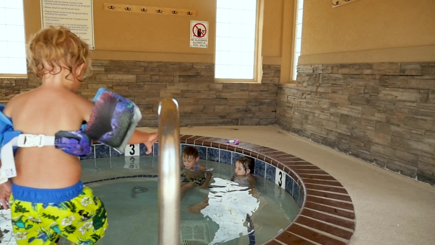 slow motion kids getting in hot tub. Little kids get into a hotel hot tub and swim around without the bubbles on in slow motion. Royalty-Free Stock Footage #1029538610