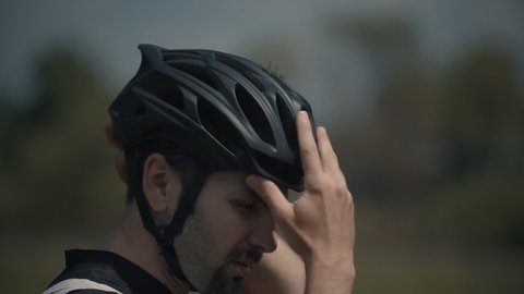 Triathlete Preparing For Cycling Triathlon Competition. Cyclist Wearing Bicycle Helmet. Professional Athlete Before Intensive Cardio Cycling Workout Exercise. Cyclist Athlete Putting On Bike Helmet