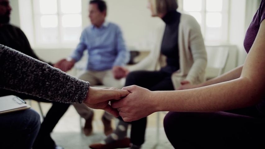 Men and women sitting in a circle during group therapy, supporting each other. | Shutterstock HD Video #1029551069