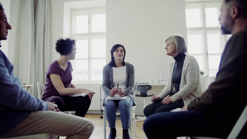 Men and women sitting in a circle during group therapy, talking. | Shutterstock HD Video #1029551072