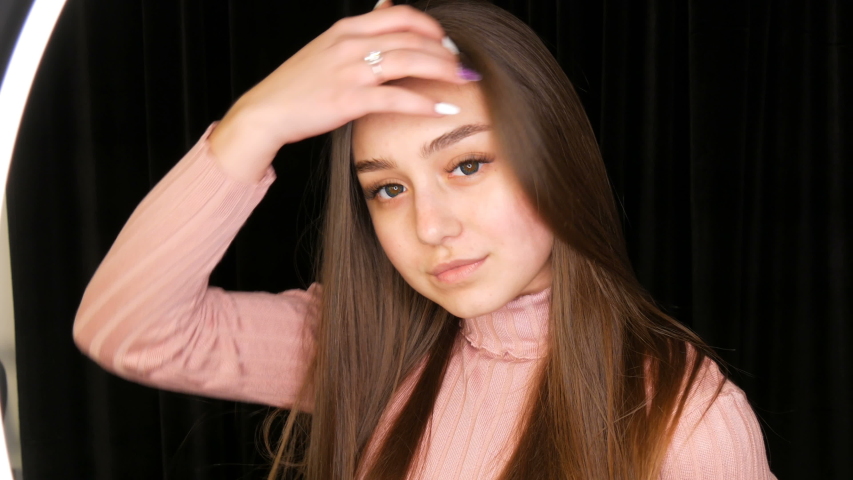 Beautiful sexy young girl without makeup long hair and cosmetic colored contact lenses posing in model studio on the black background.