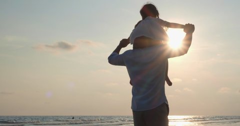 Asian kids riding on neck and shoulder of father on the beach summer. Silhouette of happy family at sunset. Concept of family, travel, silhouettes and kid dream. Parents with children back silhouette.