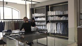 A demonstration video of shop assistants putting new collection of male clothes on the shelves. Fashion shop routine work. Receiving a new collection of clothes