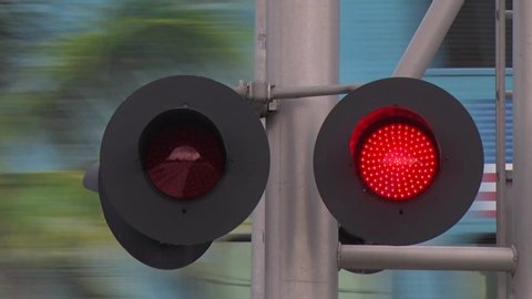 Flashing Red Railroad Crossing Lights Alternating Left to Right Indicate to Traffic to Stop as a Train Crosses in the Background