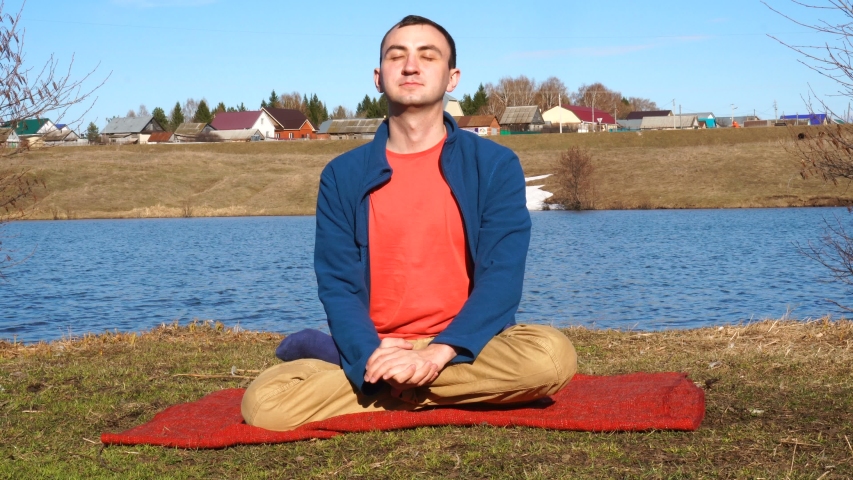 A good-looking young man doing yoga on a jetty with tropical island backdrop.