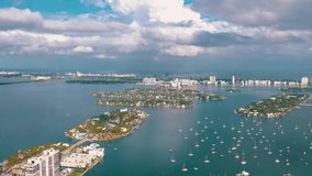 MIAMI, FLORIDA, USA - MAY 2019: Aerial drone view flight over Miami Biscayne Bay. Boats and yachts from above at sunny day with clouds. Jungle and Venetian Islands.