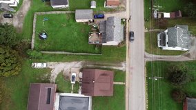 Drone flying down a street looking straight down in rural western pennsylvania town with cars passing below