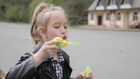 Little girl blowing soap bubbles in summer park. Slow mo video.