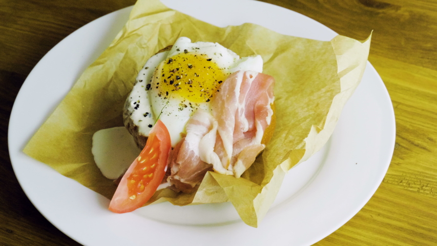English breakfast. Top view of poached egg and bacon on toast with fresh vegetables. 4K