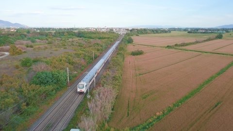 Aerial tracking of a passenger train in the countryside.