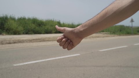 Hitchhiker's hand with a country road in background