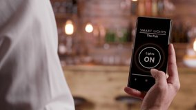 Dolly close up shot of bartender using a voice activated app to turn ON the lights in the pub he is working. Modern workplace - Powered by Shutterstock - Get 15% off with code: PIKWIZARD15