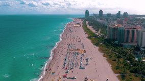 MIAMI, FLORIDA, USA - MAY 2019: Aerial drone panorama view flight over Miami beach. South Beach sand and sea from above at sunny day. Beach chairs and umbrellas on the coastline.