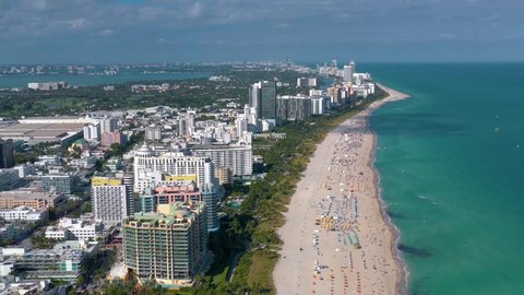 MIAMI, FLORIDA, USA - MAY 2019: Aerial drone panorama view flight over Miami beach. South Beach sand and sea from above at sunny day. Beach chairs and umbrellas on the coastline.