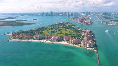 MIAMI, FLORIDA, USA - MAY 2019: Aerial drone view flight over Miami beach. South Beach and Fisher island at sunny day. Beach chairs and umbrellas on the coastline. Blue water of Goverment cut.