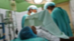 Blurred video of two surgeons doing surgery on patient in theater light 