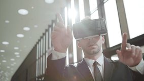 Medium shot of modern businessman in suit and tie wearing VR glasses and exploring visualization in sunlight