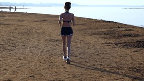Fit young woman jogging along a sandy beach
