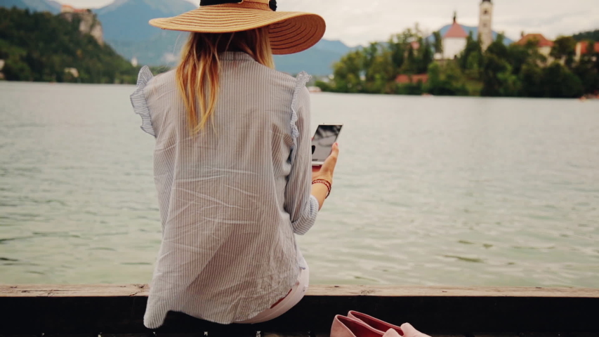 Girl on a wooden pier using smartphone.