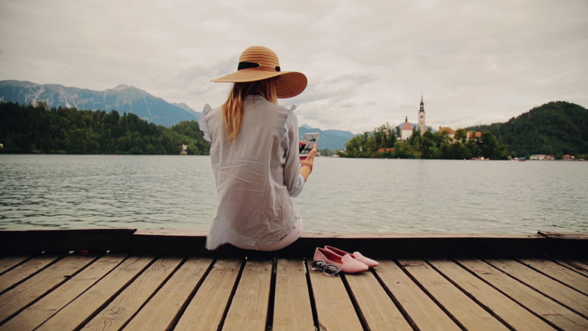 Girl on a wooden pier using smartphone.